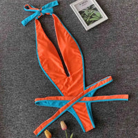 Maillot une pièce orange à liseré bleu posé à plat, lanières bleues nouées derrière le cou et tulipes à côté