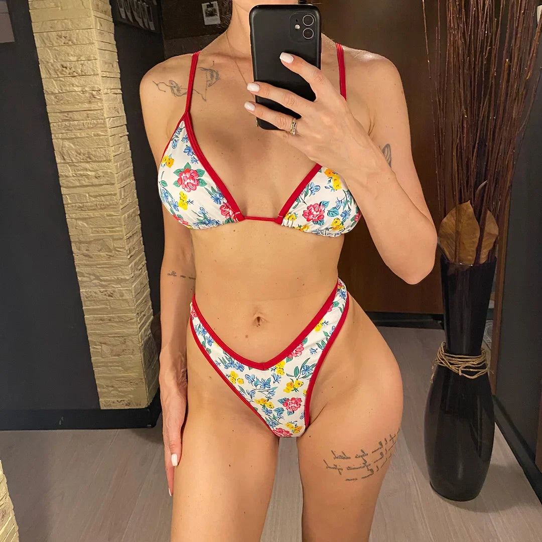 Bikini brésilien string taille basse imprimé fleuri rouge porté de face devant un miroir en pied, triangle à liseré rouge