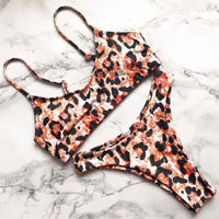 Bikini sans armatures orange à motif léopard étalé à plat sur un marbre blanc, bretelles fines du haut bien visibles