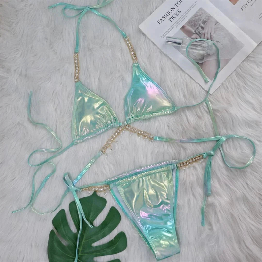 Bikini aspect simili cuir vert irisé posé à plat sur une fourrure blanche, avec une feuille verte