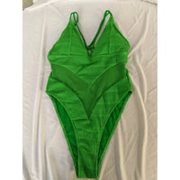 Maillot de bain une pièce échancré vert posé à plat sur un drap blanc, col V et insert transparent
