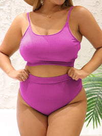 Bikini deux pièces grande taille côtelé taille haute rose fuchsia porté de face, mains sur les hanches, plante verte à droite