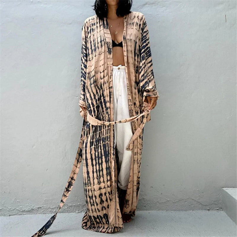 Tunique de plage imprimée manches longues à ceinture noir et beige portée de face avec un pantalon blanc, ceinture nouée