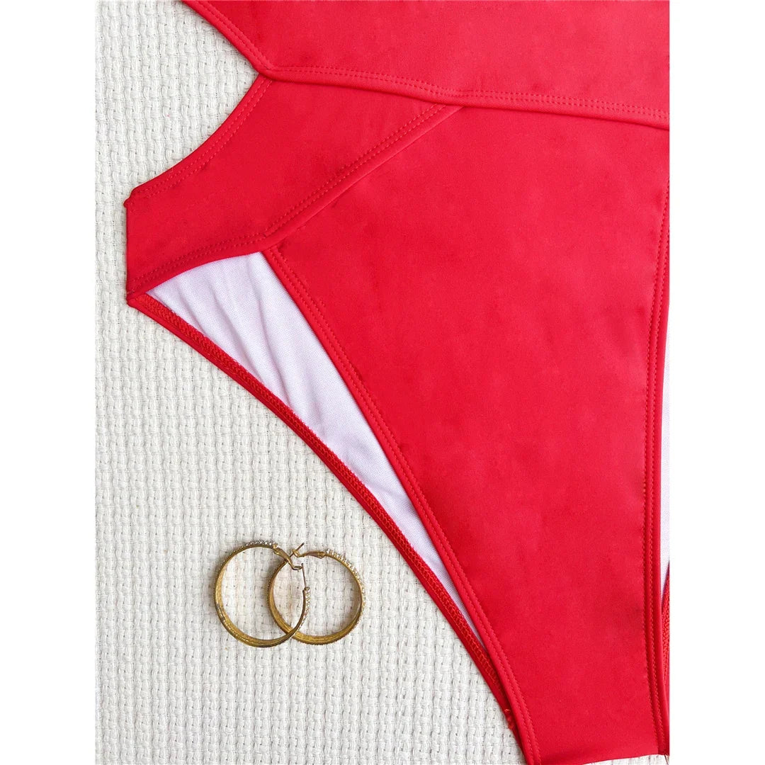 Gros plan sur la découpe latérale du maillot une pièce rouge, doublure blanche visible et deux anneaux dorés en bas