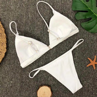Bikini brésilien rembourré à taille basse blanc posé à plat, anneau central du triangle et feuille verte