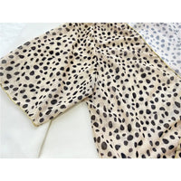 Gros plan sur le tissu imprimé léopard du maillot trois pièces taille haute, taches noires sur fond beige
