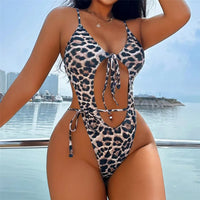Maillot de bain une pièce échancré à nœud imprimé léopard porté de face, mains sur la taille, cordons visibles
