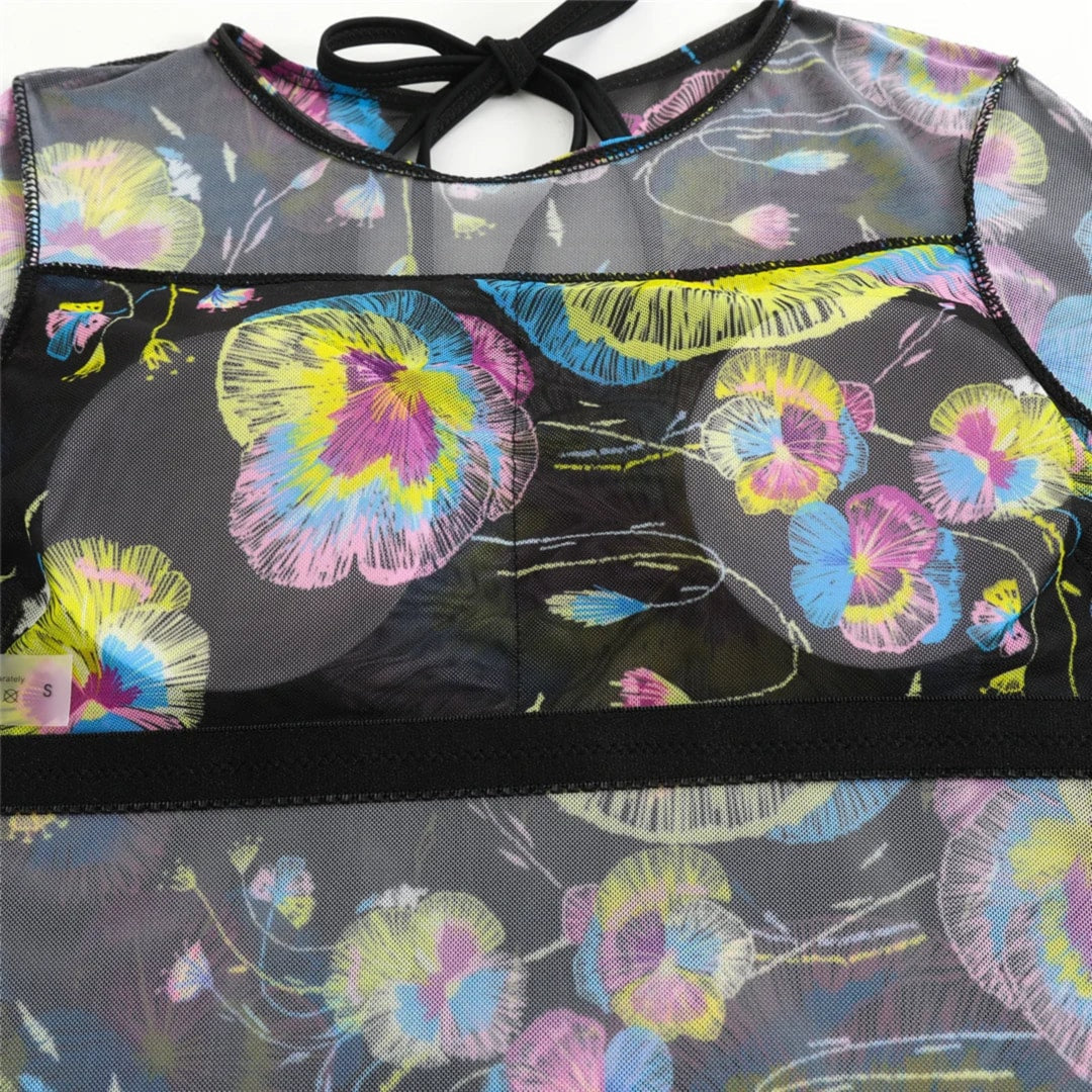 Gros plan sur le buste du body en mesh noir à fleurs jaunes, roses et bleues, bande noire au niveau de la poitrine