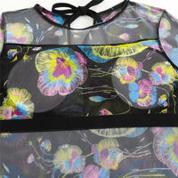 Gros plan sur le buste du body en mesh noir à fleurs jaunes, roses et bleues, bande noire au niveau de la poitrine