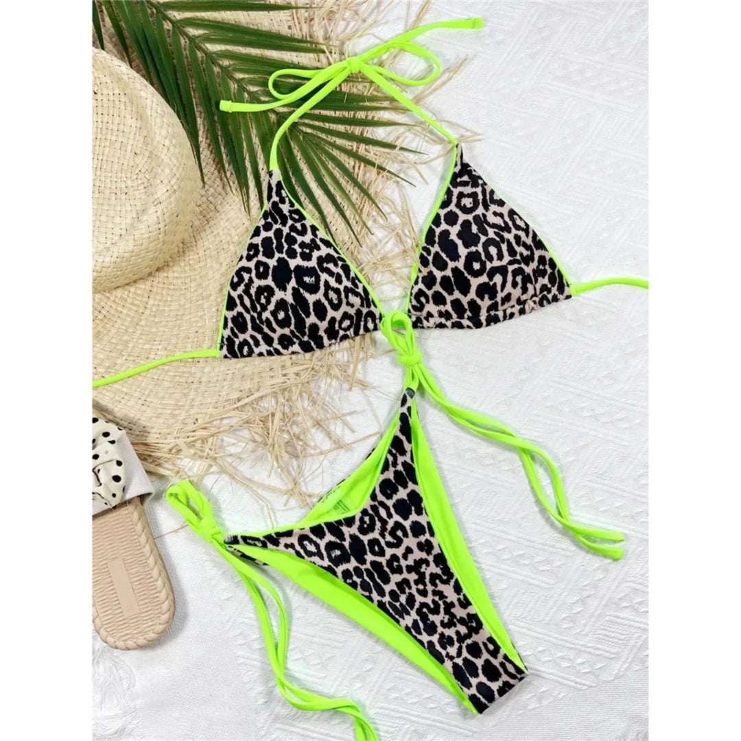 Bikini brésilien triangle imprimé léopard beige et noir à liserés vert fluo posé à plat sur un tissu blanc