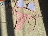 Bikini bandeau texturé rose poudré à lacets et étoile de mer, vu à plat montrant la doublure blanche intérieure