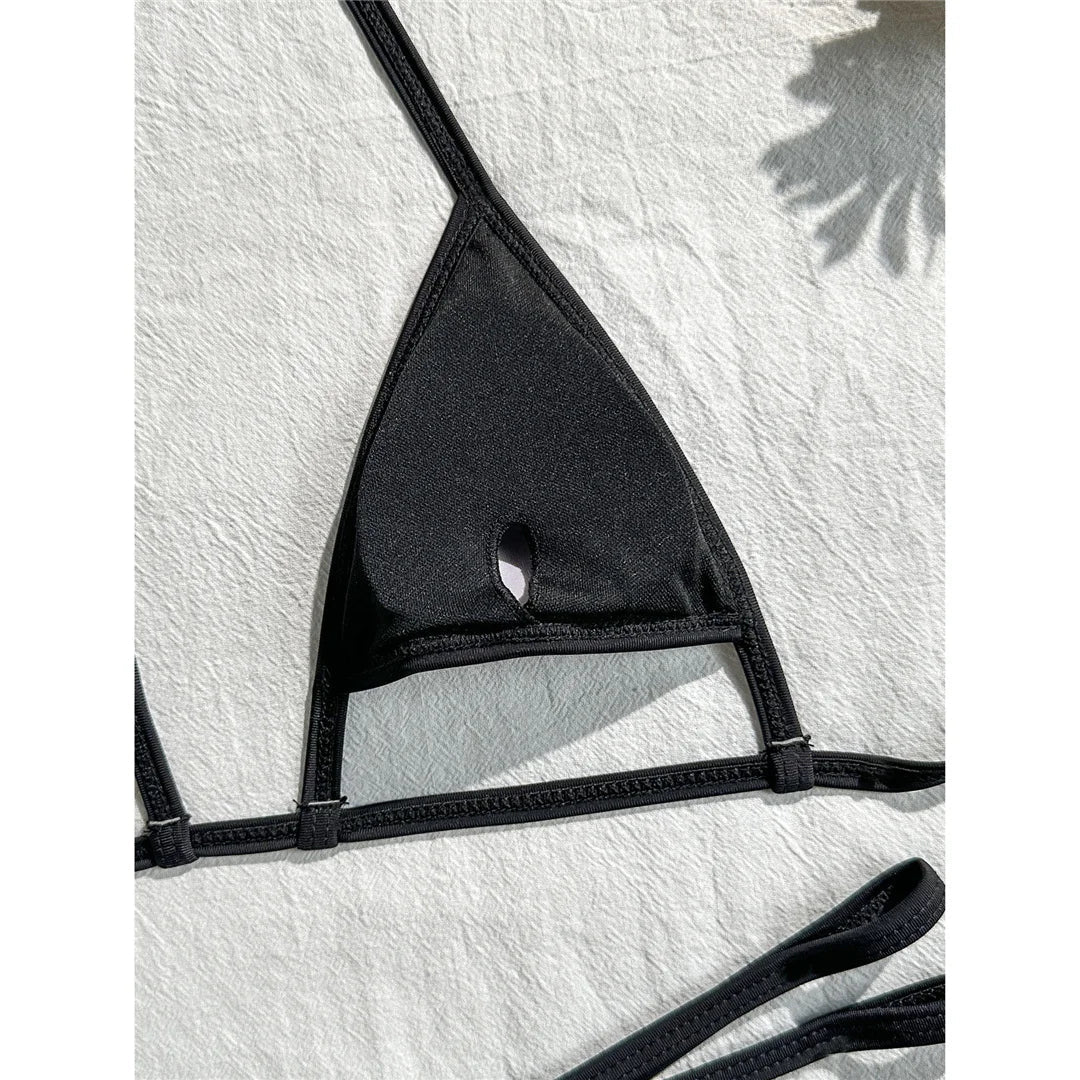 Gros plan sur l'intérieur uni du triangle noir d'un bikini string micro, petite ouverture au centre