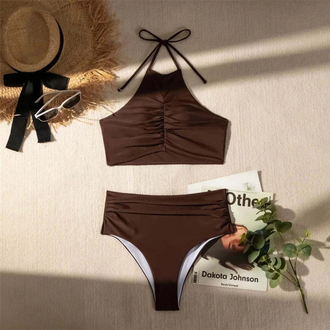 Bikini taille haute tour de cou texturé marron café posé à plat sur une table, avec chapeau de paille et livre à côté