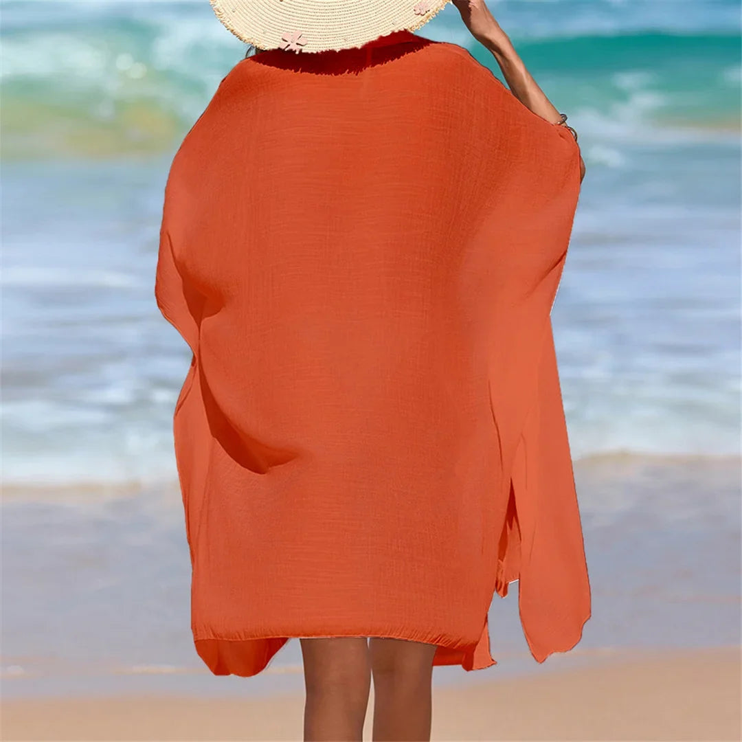 Chemise de plage longue à manches courtes en maille orange vue de dos avec chapeau de paille sur la tête, mer en arrière-plan