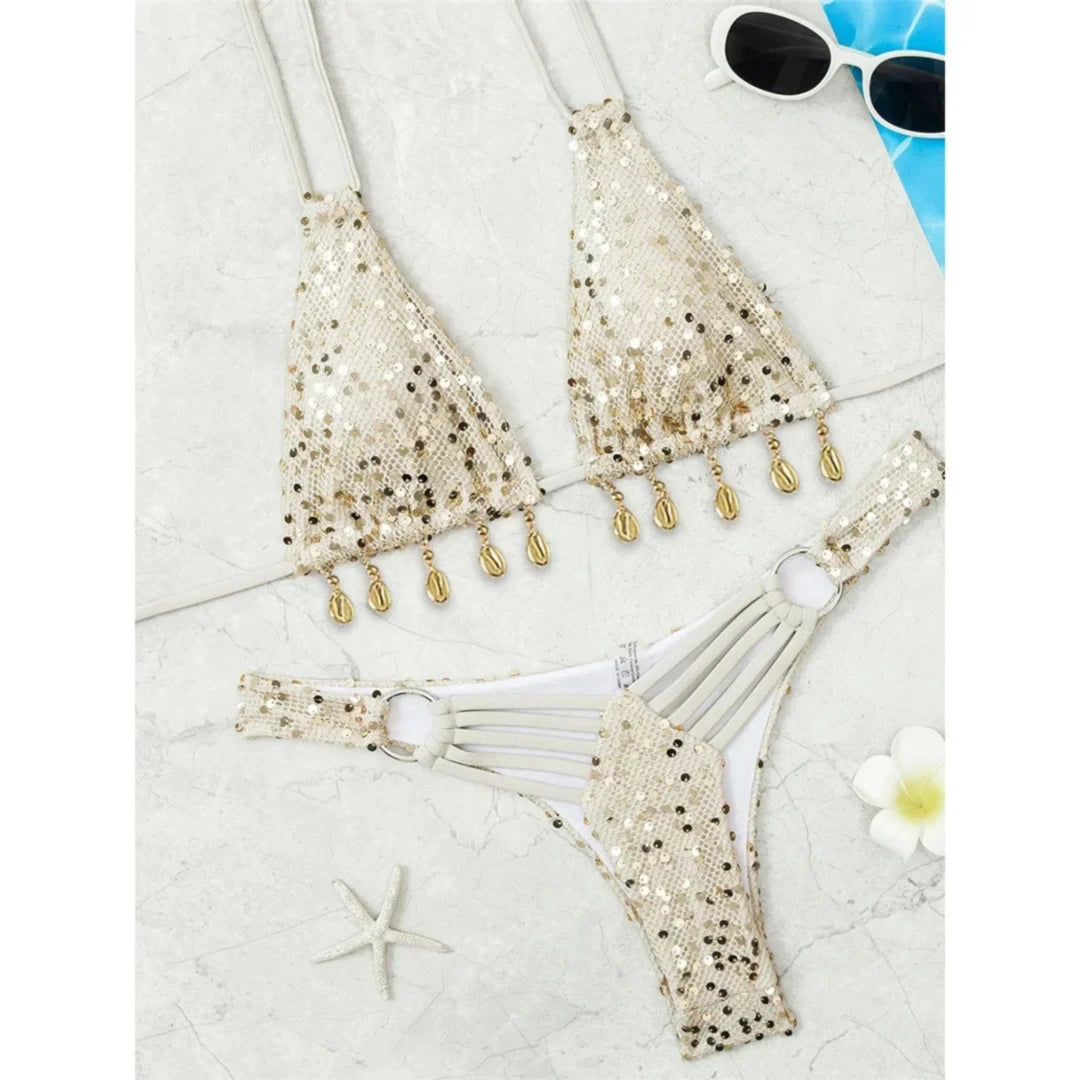 Bikini brésilien beige brillant à sequins dorés et coquillages, posé à plat avec une étoile de mer et une fleur