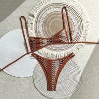 Bikini triangle échancré imprimé rouge brique à motifs vagues beiges posé à plat sur des sets de table en paille