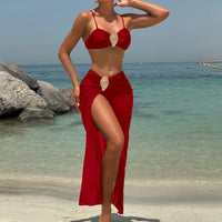 Maillot trois pièces rouge porté de face, bras levé, jupe longue à fente latérale et anneau doré sur la taille