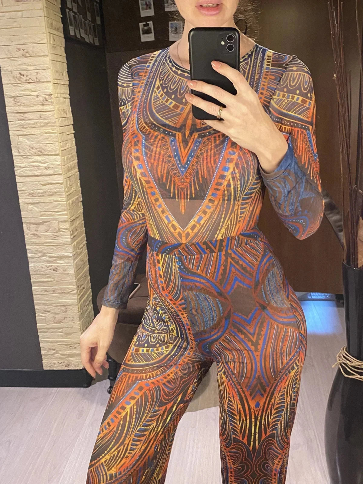 Maillot de bain une pièce manches longues et pantalon bleu à motifs orange, porté de face par une femme devant un miroir