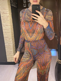 Maillot de bain une pièce manches longues et pantalon bleu à motifs orange, porté de face par une femme devant un miroir