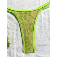 Gros plan sur le bas en dentelle vert fluo du bikini string micro, bretelles doubles sur les hanches