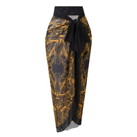 Paréo long jaune à motifs dorés noué à la taille, posé à plat sur fond blanc, assorti au maillot