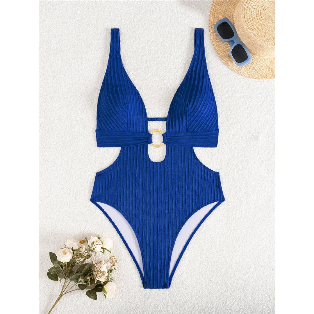 Maillot de bain une pièce décolleté plongeant bleu marine à plat sur fond blanc, avec lunettes et fleurs