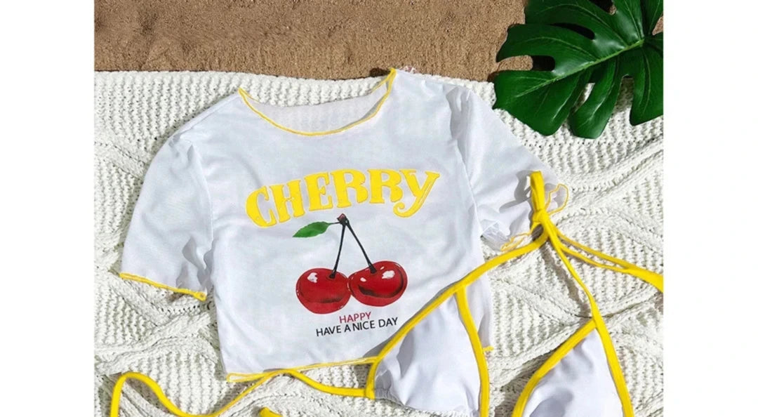 Gros plan sur le haut du maillot trois pièces crop top cerises blanc bordé jaune