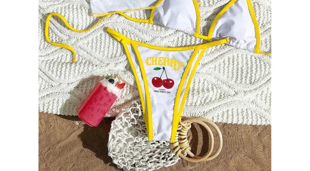 Gros plan sur le bas du maillot trois pièces crop top cerises blanc bordé jaune