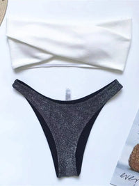 Bikini bandeau scintillant à paillettes noir posé à plat sur fond blanc, haut blanc torsadé et bas pailleté noir