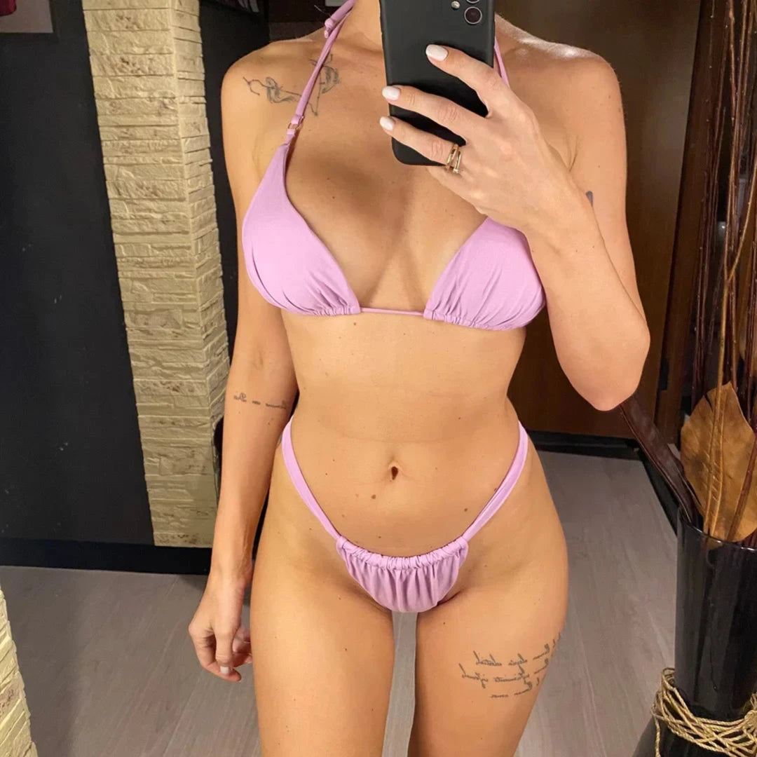 Bikini string triangle froncé violet porté de face devant un miroir, bretelles nouées au cou et bas froncé