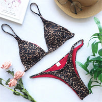 Bikini brésilien sans armatures imprimé léopard à plat près de fleurs roses, doublure rouge visible sur le slip