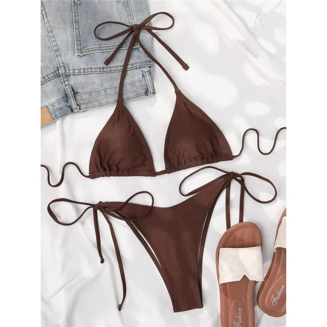 Bikini brésilien tour de cou rembourré uni marron posé à plat sur une veste en jean et des sandales en cuir