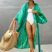 Tunique de plage imprimée manches longues à ceinture vert portée de face avec un grand sac en osier au bras