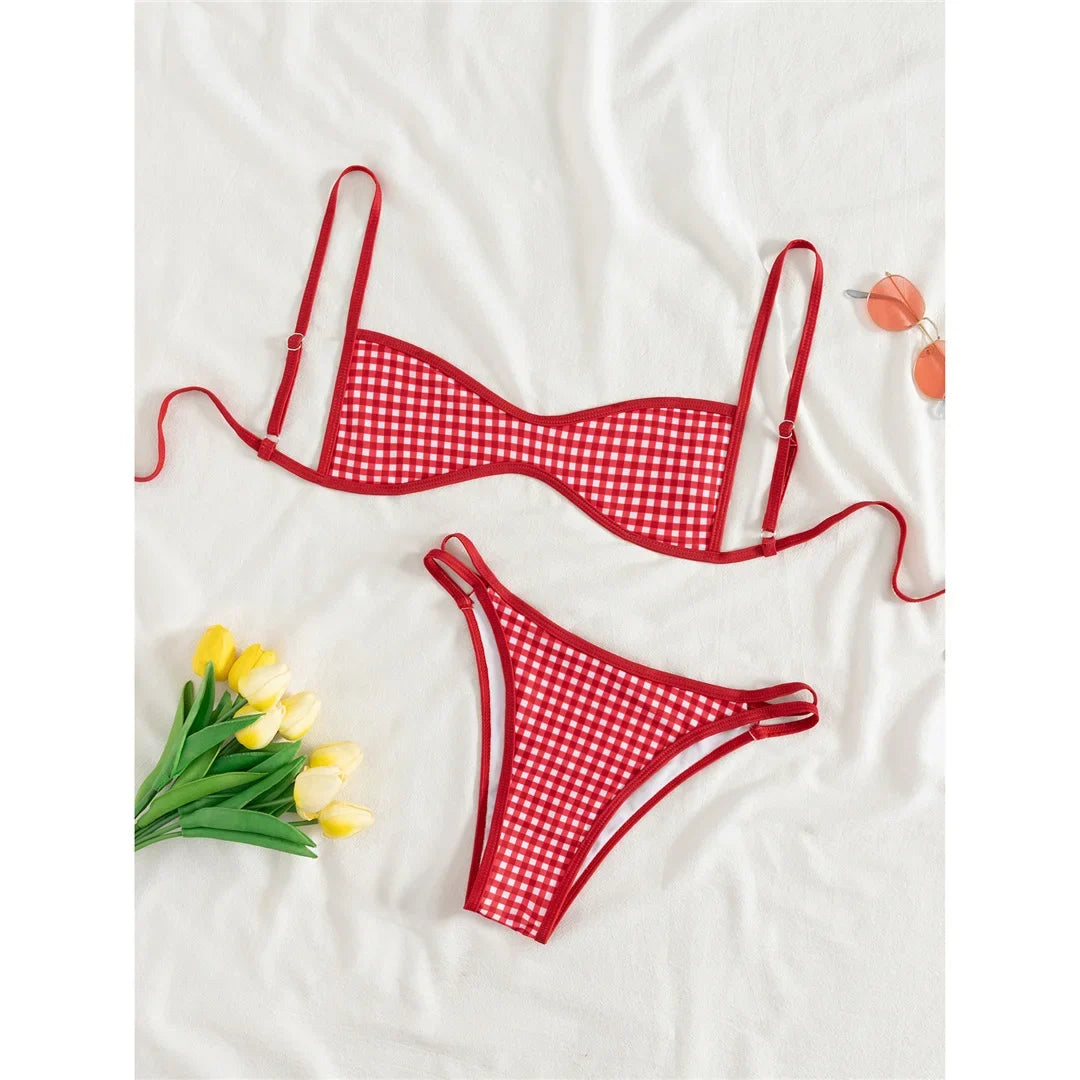 Bikini triangle sans coques à carreaux rouge posé à plat sur un drap blanc, bretelles réglables et bas à double bride