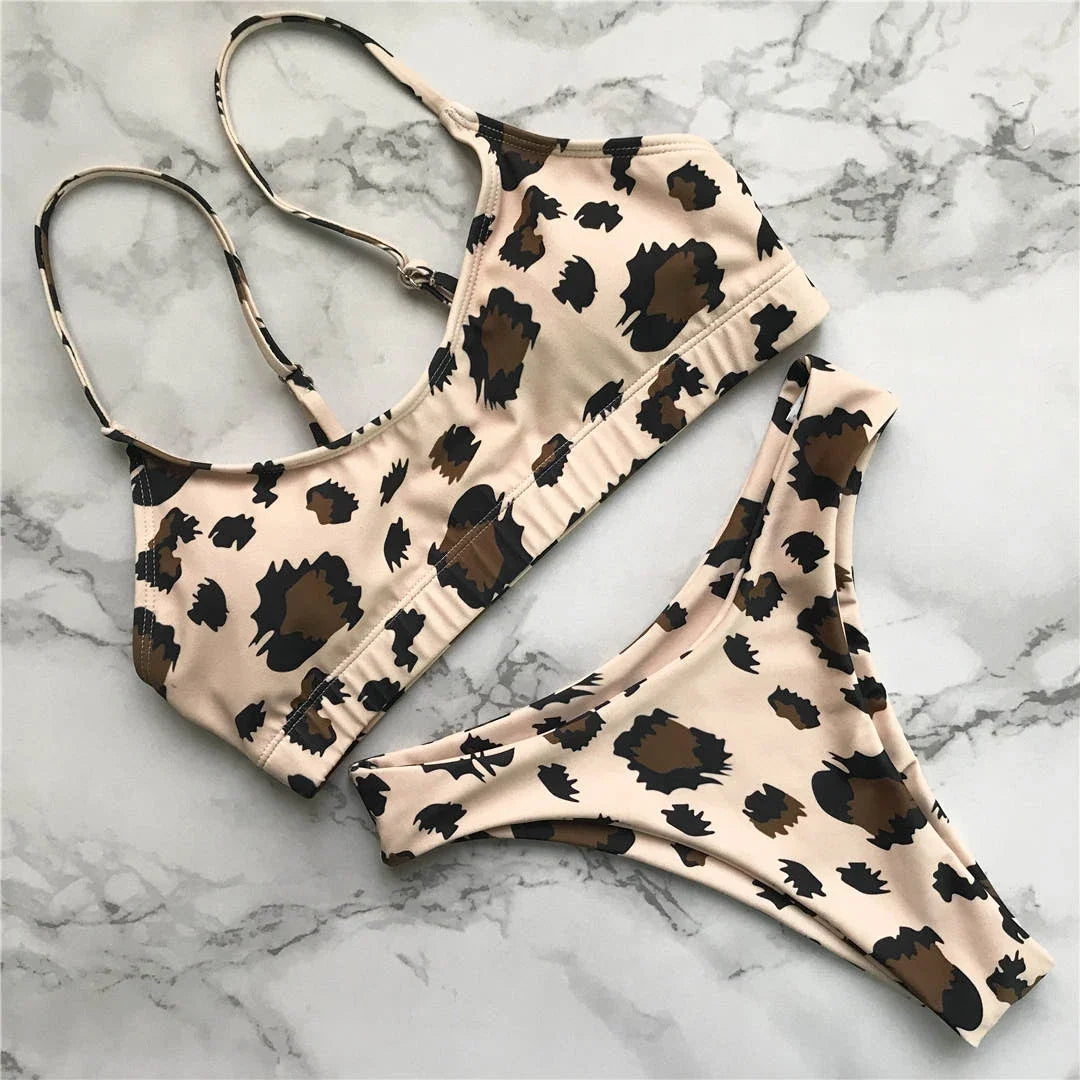Bikini triangle brésilien à bretelles réglables beige à imprimé léopard posé à plat sur marbre blanc, haut à bretelles fines et bas assorti