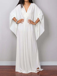 Robe de plage longue kaftan manches chauve-souris blanc portée de face en pied, mains aux hanches et fente latérale au bas