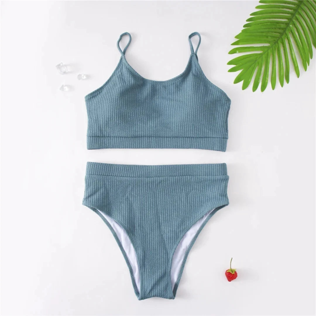 Bikini deux pièces grande taille côtelé taille haute bleu gris à plat sur fond blanc, avec une feuille verte et une cerise