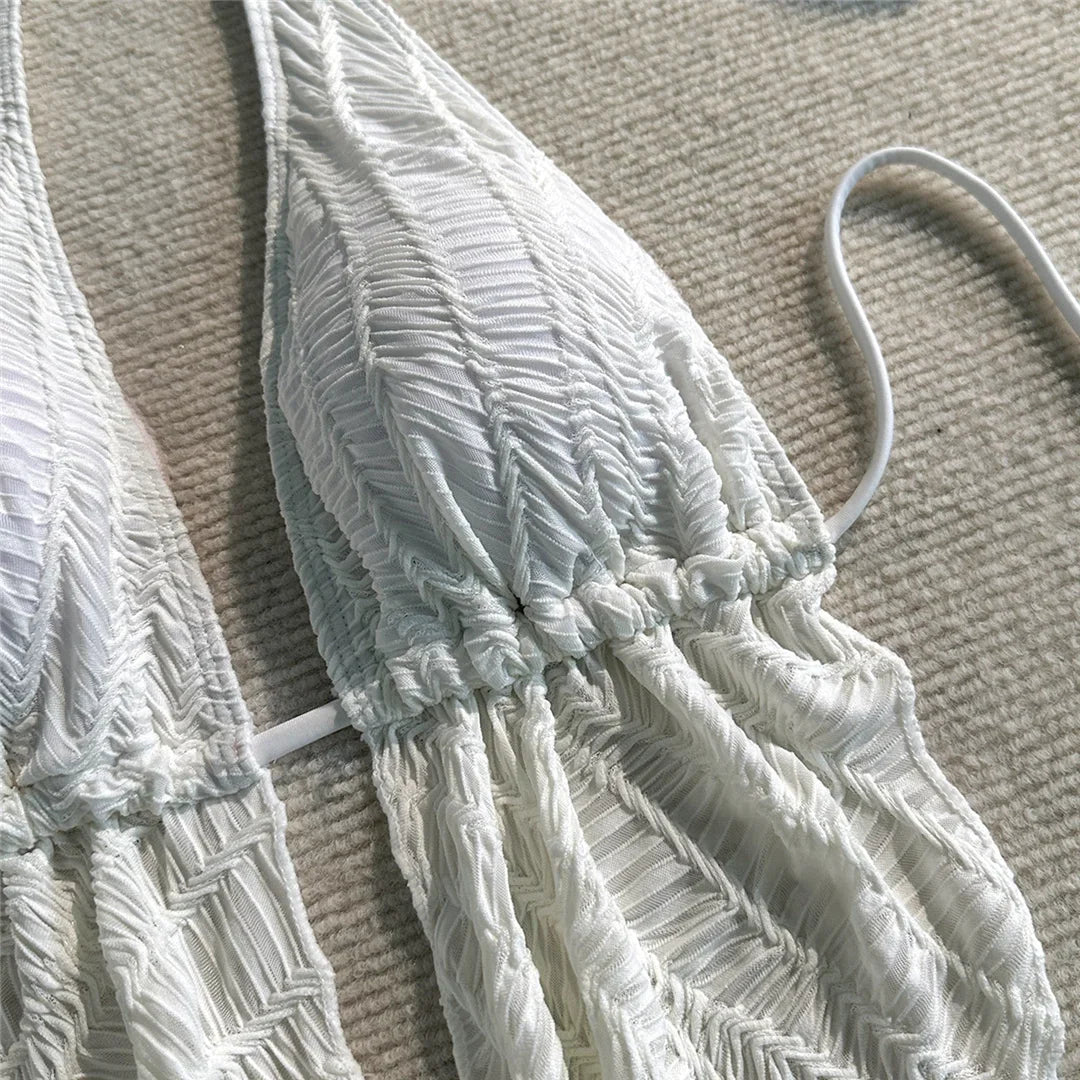 Gros plan sur le haut texturé blanc du maillot de bain trois pièces, tissu froncé au centre et bretelle fine