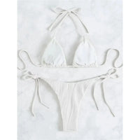 Bikini brésilien tour de cou froncé texturé blanc à plat sur du marbre blanc, lacets latéraux longs