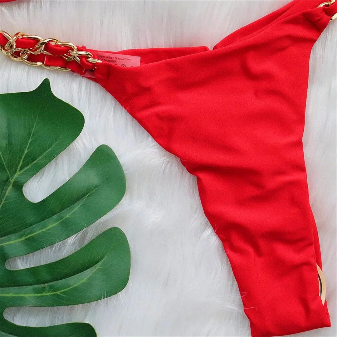 Gros plan sur le bas rouge et son anneau métallique doré sur fond blanc, feuille de monstera en arrière-plan