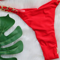 Gros plan sur le bas rouge et son anneau métallique doré sur fond blanc, feuille de monstera en arrière-plan