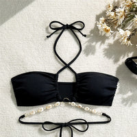 Bikini bandeau côtelé noir tour de cou, ornement de coquillages et lacets croisés dans le dos, vu à plat sur fond clair