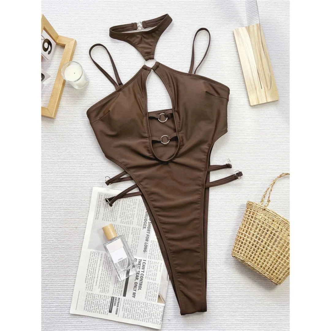 Maillot de bain une pièce marron café posé à plat sur fond clair, col tour de cou, anneaux et découpes latérales