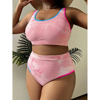 Bikini grande taille tie-dye taille haute rose de face sous un chapeau de paille, feuillage en fond