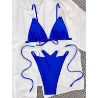 Bikini bleu roi à brides perlées posé à plat sur chemise blanche, perles sur les bretelles du haut