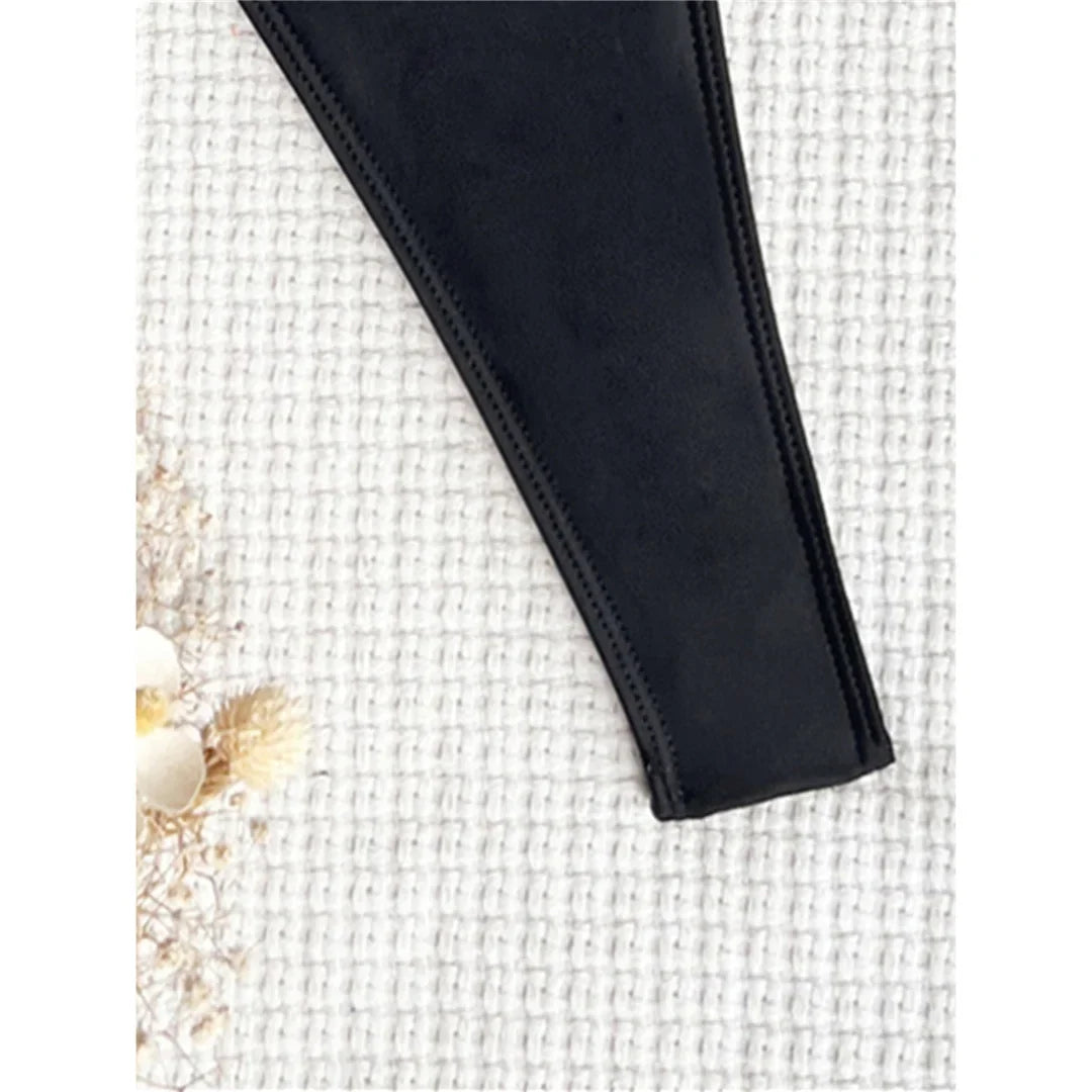 Gros plan sur le bord latéral échancré d'un maillot une pièce noir posé sur un tissu blanc