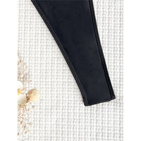 Gros plan sur le bord latéral échancré d'un maillot une pièce noir posé sur un tissu blanc