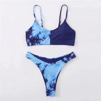 Bikini sans armatures bleu imprimé étalé à plat sur un tapis pastel, haut bleu marine à moitié tie-dye et bas tie-dye