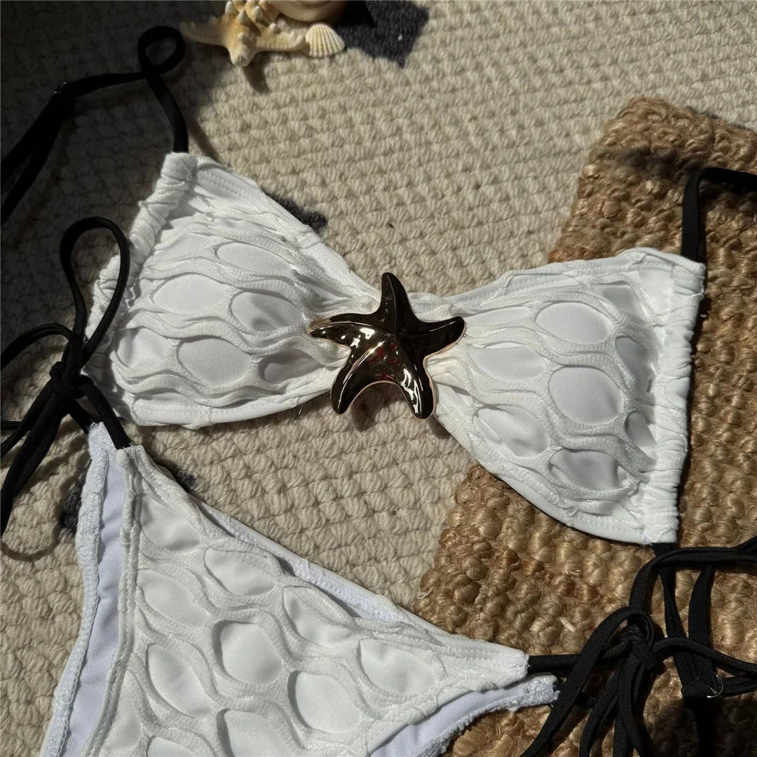 Gros plan sur l'étoile métal dorée du bikini blanc échancré, bonnet texturé en relief et lanières noires
