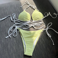 Bikini col halter croisé à effet froissé vert clair posé à plat, longs lacets blancs et slip à nouer sur les côtés